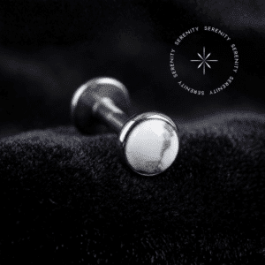 piercing topo pedra natural branca titânio repousando suavemente sobre um tecido de cetim branco de alta opulência, destacando o polimento profundo do titânio e o contraste da gema.