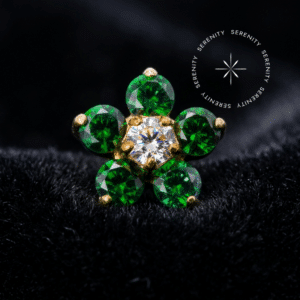 Topo Flor Cravejado em Titânio Dourado exibindo vibrantes pétalas em Zircônia Verde e um ponto de luz central em Zircônia Translúcida, com acabamento impecável.